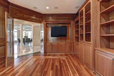 Luxurious wooden paneled room with TV, bookshelves, and open doors to dining area.